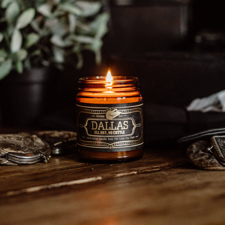 Jackson Vaughn Dallas Candle – tall lit amber candle jar on a wooden table